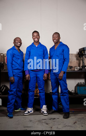 Three African mechanics standing in a workshop smiling at the camera Stock Photo