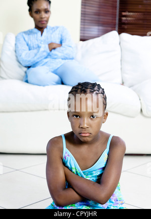 Young African girl frowning with mother in background Stock Photo