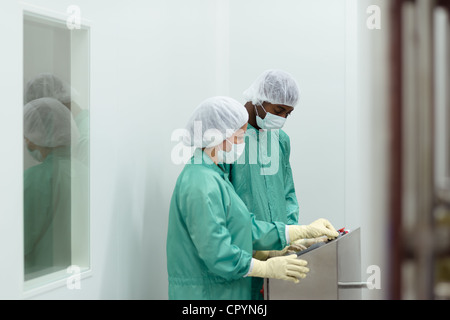 Laboratory technicians at work in medical plant with machinery and computers Stock Photo