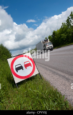 lorry passing no overtaking warning sign due to loose chippings on newly resurfaced road uk Stock Photo