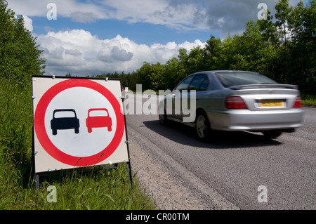 car passing no overtaking warning sign due to loose chippings on newly resurfaced road uk Stock Photo