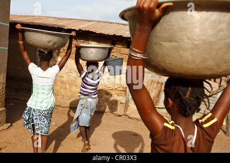 Girls carry water containers they filled from a communal well in the village of Kiendi-Walogo, Zanzan region, Cote d'Ivoire Stock Photo