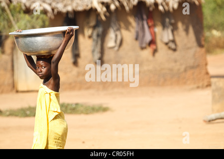 A girl who doesn't go to school heads out to fetch water in the village of Djorbana, Zanzan region, Cote d'Ivoire Stock Photo