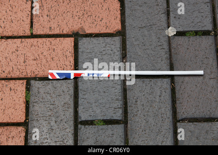 Remnants of a torn Union Jack flag discarded in block paved city center public area. Stock Photo