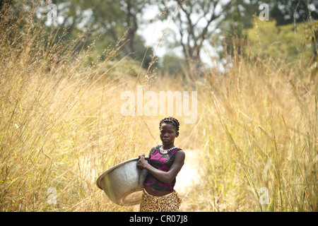 Kambou Tangba, 17, stands along a path as she heads to the field to work in the village of Kirkpadouo, Zanzan region Stock Photo