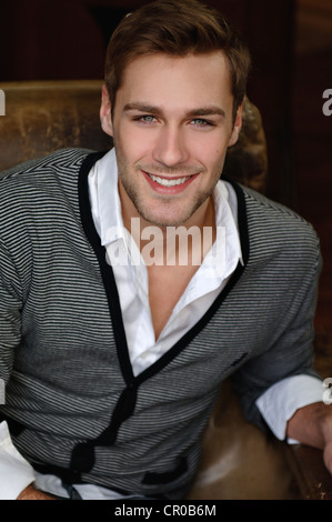 Portrait of a young man in a cardigan sitting in a leather chair Stock Photo