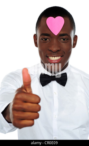 Heart shaped sticky note on african mans forehead gesturing thumbs-up Stock Photo