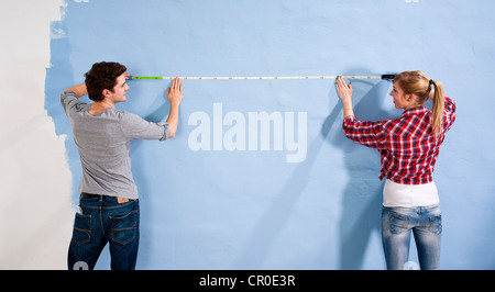 Young couple measuring a wall Stock Photo