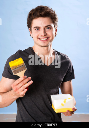 Smiling young man holding a paintbrush in his hand Stock Photo