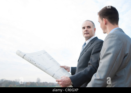 Two architects discussing a construction plan outdoors Stock Photo