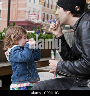 A father blows bubbles for his daughter to enjoy in Brooklyn, New York. Stock Photo