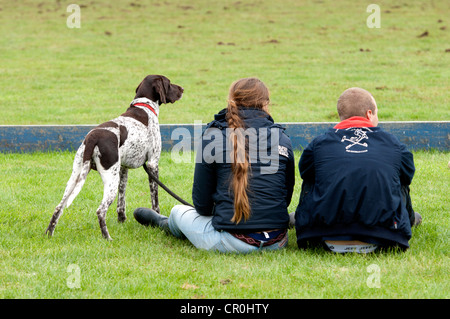 Two students with German Pointer dog watching a polo match Stock Photo