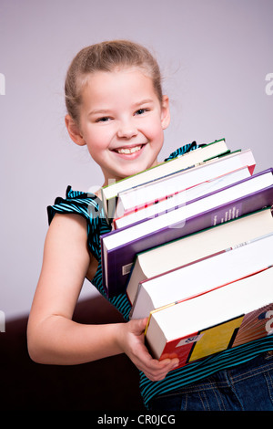 Girl, 8, carrying a stack of books Stock Photo - Alamy