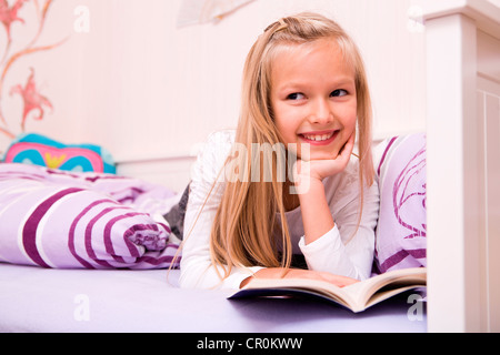 Girl reading a book in bed Stock Photo