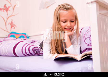Girl reading a book in bed Stock Photo