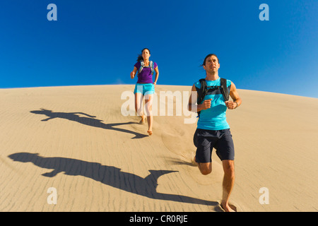 Hispanic couple running on sand dune Stock Photo