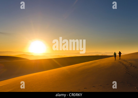 Hispanic couple walking on sand dune at sunset Stock Photo