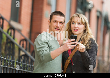 USA, New Jersey, Jersey City, Couple using smart phone on street Stock Photo
