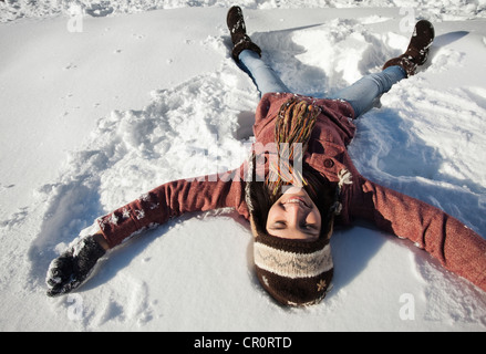 Caucasian woman making snow angel Stock Photo