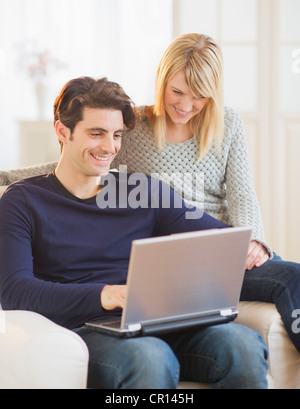USA, New Jersey, Jersey City, Couple sitting together on armchair and using laptop Stock Photo