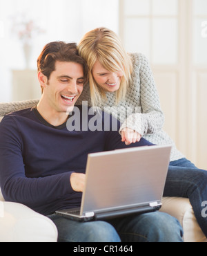 USA, New Jersey, Jersey City, Happy couple sitting together on armchair and using laptop Stock Photo