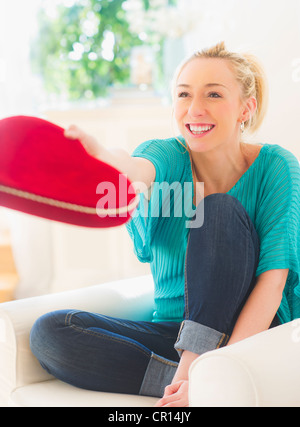 USA, New Jersey, Jersey City, Smiling young woman holding box of chocolates in heart shape Stock Photo