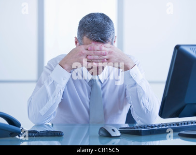 Portrait of depressed businessman sitting at desk Stock Photo
