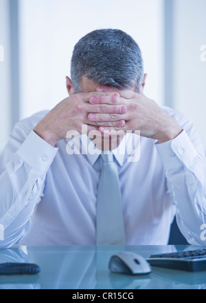 Portrait of depressed businessman sitting at desk Stock Photo