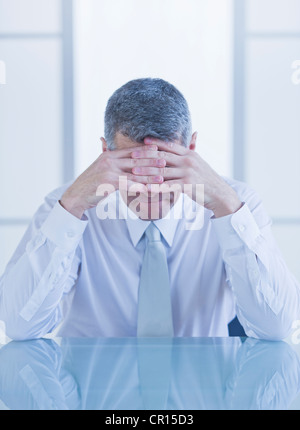 Portrait of depressed businessman sitting at desk Stock Photo