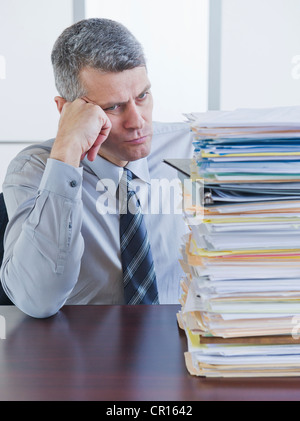 Businessman looking at large stack of documents Stock Photo