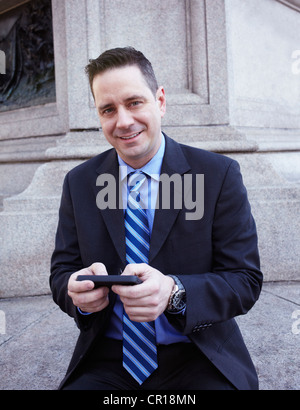 USA, New York, New York City, Portrait of businessman with smartphone Stock Photo