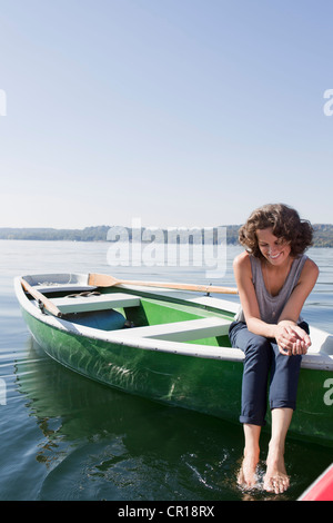 Woman dangling feet from boat in lake Stock Photo
