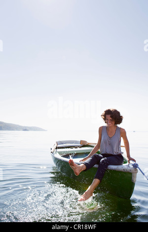 Woman dangling feet from boat in lake Stock Photo