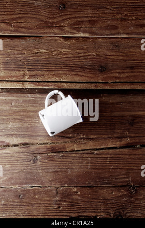 Old enamel cup hanging on a rustic wooden wall Stock Photo