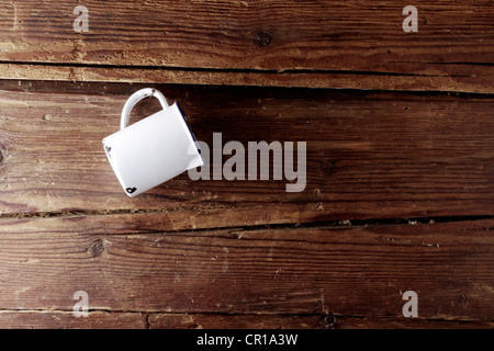 Old enamel cup hanging on a rustic wooden wall Stock Photo