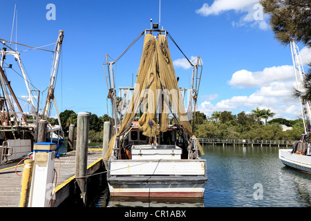 Fishing boats at rest in river estuary moored at a pier Stock Photo