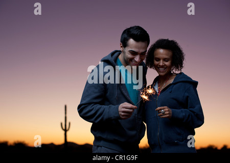 Couple playing with sparklers in desert Stock Photo