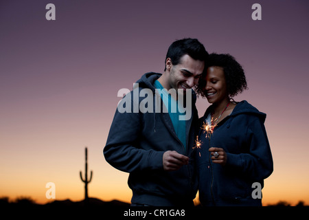 Couple playing with sparklers in desert Stock Photo