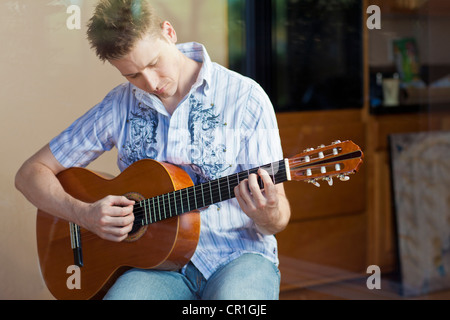 Man playing guitar in living room Stock Photo