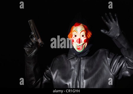 Man in clown mask holding gun Stock Photo