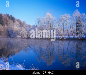 Snow-covered trees reflected in the Loisach river near Eurasburg, Eurasburg Castle in the back, Upper Bavaria, Bavaria Stock Photo