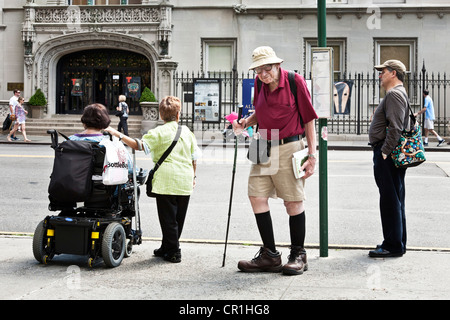 4 people waiting for bus on E 79th Street include including magnificent old man with twinkle in his eye & large feet Manhattan Stock Photo