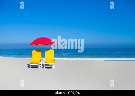 Empty lawn chairs and umbrella on beach Stock Photo