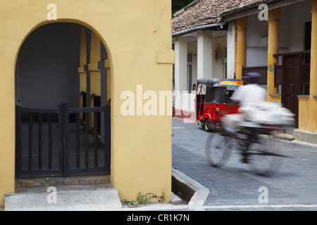 Man cycling along street, Galle, Southern Province, Sri Lanka Stock Photo