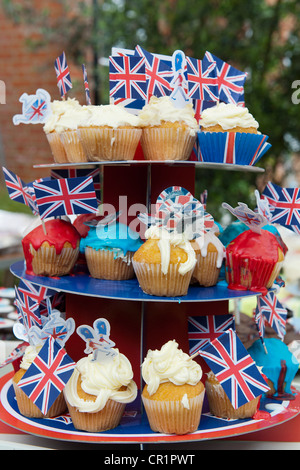 Cakes, bunting, face paint and champagne are enjoyed at a street party in South West London despite the odd burst of rain. Stock Photo