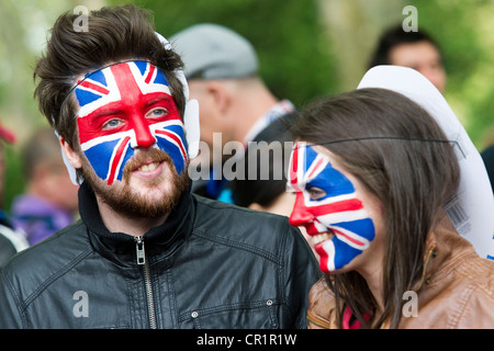 Patriotic Londoners mingle with tourists on the Mall to celebrate the Queen's Jubilee. Union Jack face paint and flags abound. Stock Photo