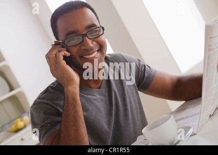 USA, California, Los Angeles, Mature man talking via mobile while holding newspaper Stock Photo