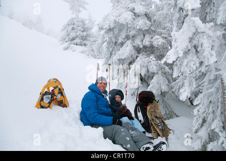 Father and son resting while snowshoeing Stock Photo