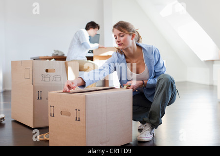Woman taping up cardboard box Stock Photo