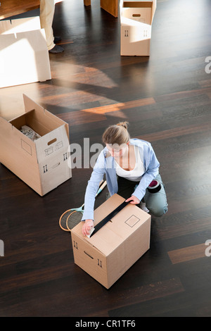 Woman taping up cardboard box Stock Photo